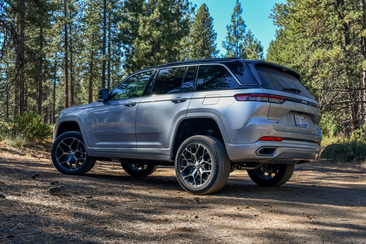 A 2024 Jeep Grand Cherokee 4xe Summit Reserve parked on a dirt road, surrounded by trees